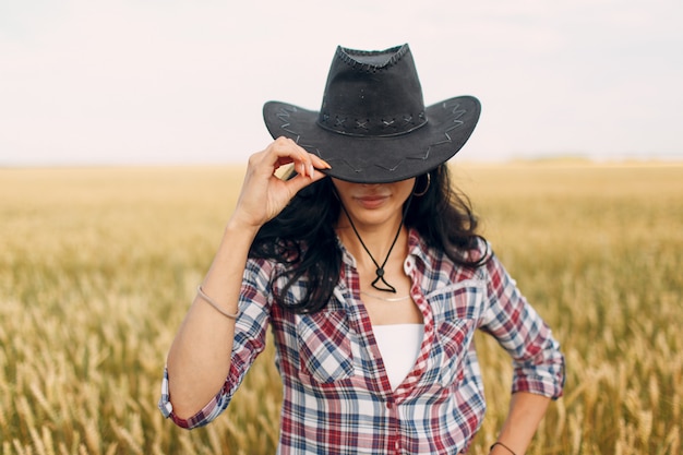 Fermier portant chapeau de cowboy, chemise à carreaux et jeans au champ de blé