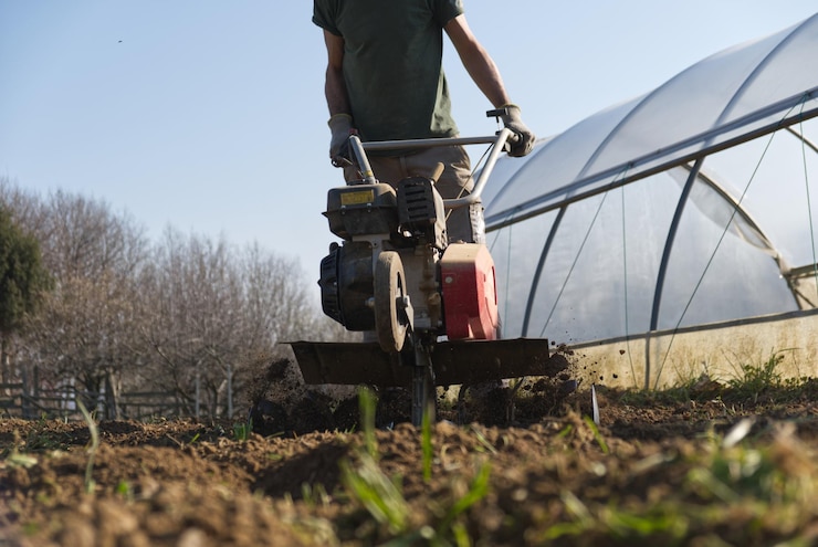 Photo un fermier prépare le sol pour le jardin potager d'été avec une tondeuse