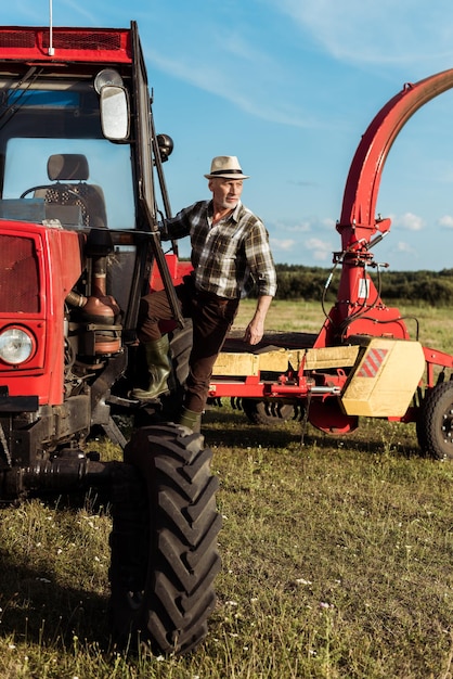 Photo fermier senior indépendant près d'un tracteur moderne