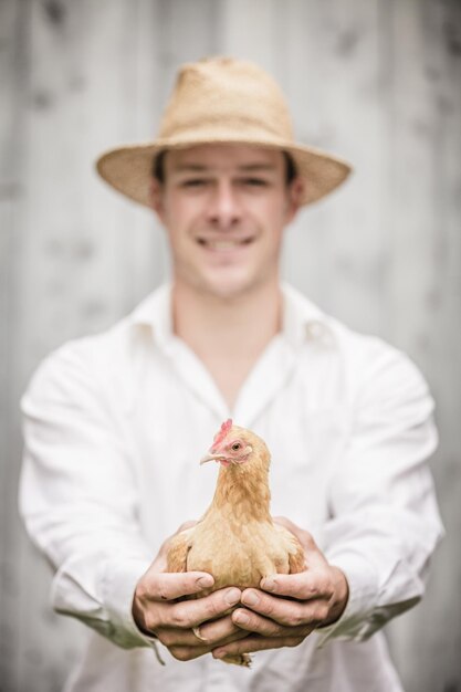 Photo fermier tenant un poulet beige