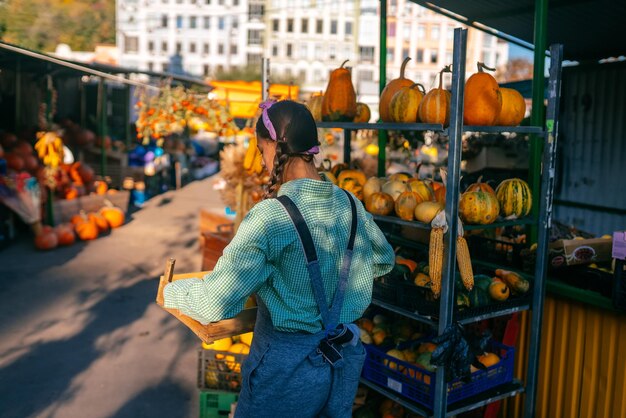 La fermière porte une boîte en bois pour les petites citrouilles