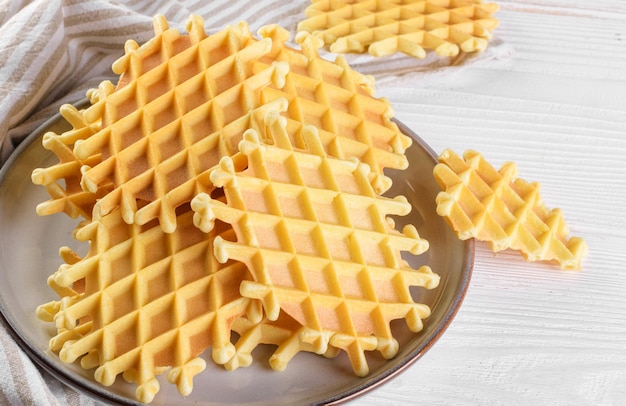 Ferratelle ou pizzelle un dessert traditionnel ou des biscuits des Abruzzes sur une assiette sur un fond en bois blanc gros plan