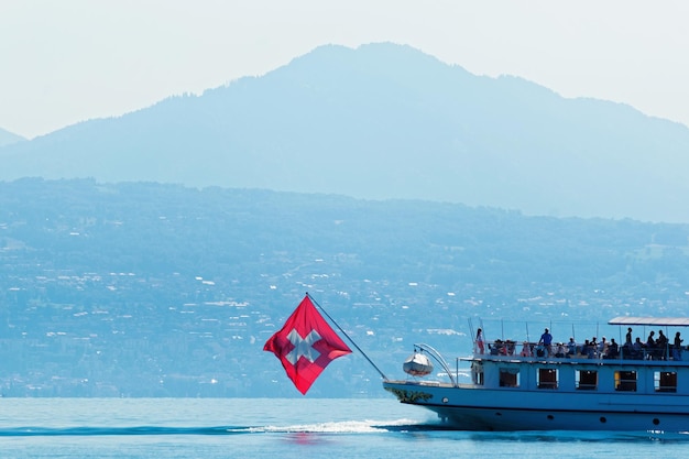 Ferry à eau avec drapeau suisse dans le lac Léman au remblai d'Ouchy à Lausanne, Suisse. Personnes à bord