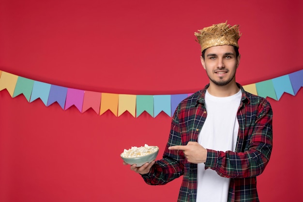 Festa junina heureux mec mignon portant un chapeau de paille célébrant le festival brésilien avec du pop-corn