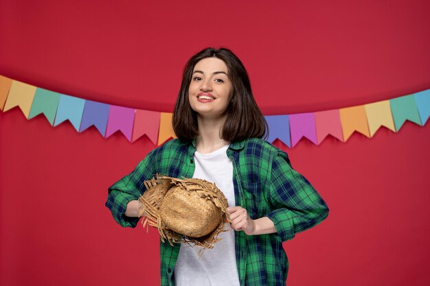 Festa junina jolie jeune fille en chemise verte célébrant le festival brésilien tenant un chapeau de paille