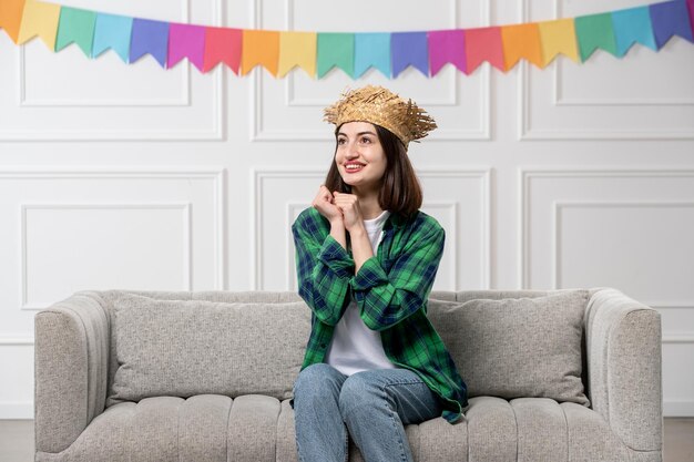 Festa junina jolie jolie fille en chemise verte chapeau de paille avec des drapeaux colorés main dans la main ensemble