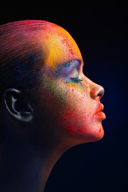 Festival des couleurs Holi. Art du visage féminin avec maquillage créatif. portrait de jeune mannequin avec un mélange coloré et lumineux de peinture.