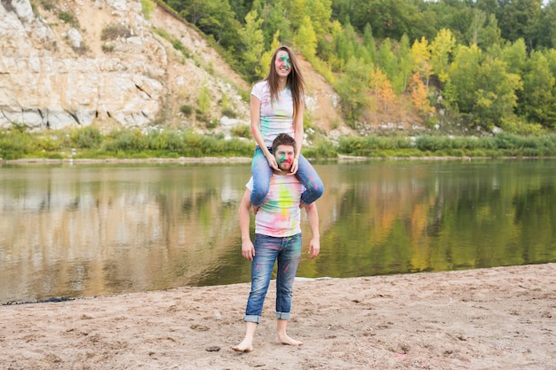 Festival holi, tourisme d'été et concept nature - jeune femme séduisante assise sur son petit ami sur la nature