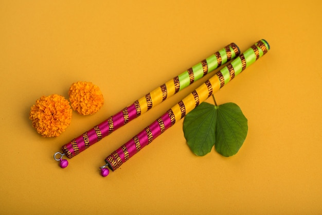 Photo festival indien de dussehra et navratri, montrant des feuilles d'or (bauhinia racemosa) et des fleurs de souci avec des bâtons de dandiya.