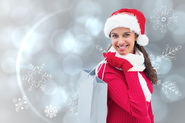 Festive brunette holding shopping bag contre la conception de modèle de flocon de neige argenté