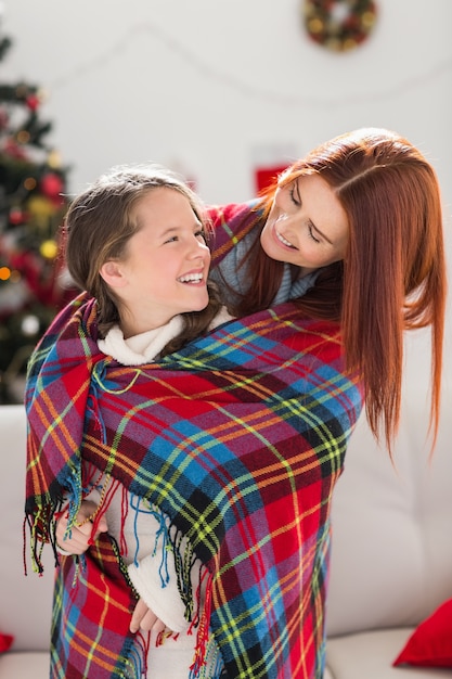 Festive mère et fille enveloppée dans une couverture