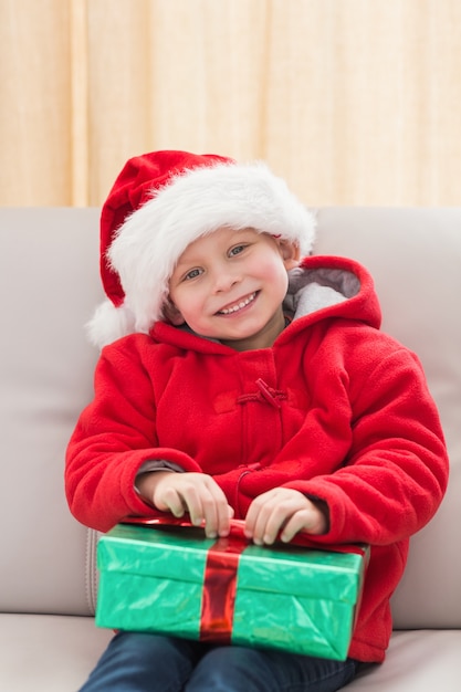 Festive petit garçon souriant à la caméra avec cadeau