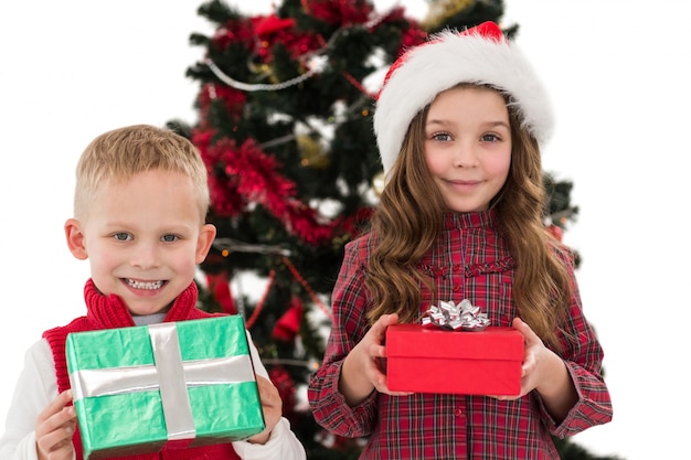 Festive petits frères et sœurs, souriant à la caméra tenant des cadeaux