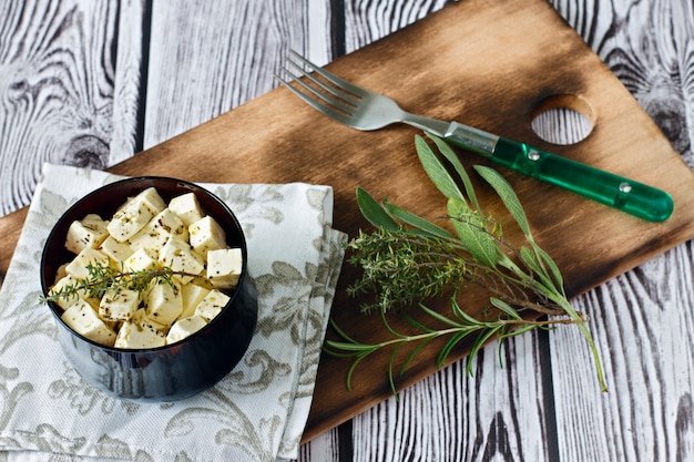 Feta marinée dans une assiette sur une planche de bois sur un fond en bois