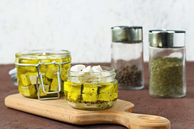 Feta marinée dans un bocal en verre et épices sur fond blanc