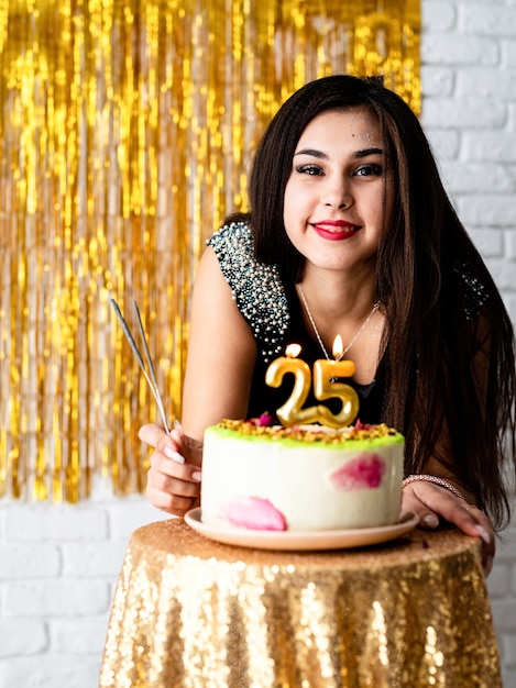 Fête d'anniversaire. Belle femme en robe de soirée noire célébrant son anniversaire prête à souffler des bougies sur le gâteau