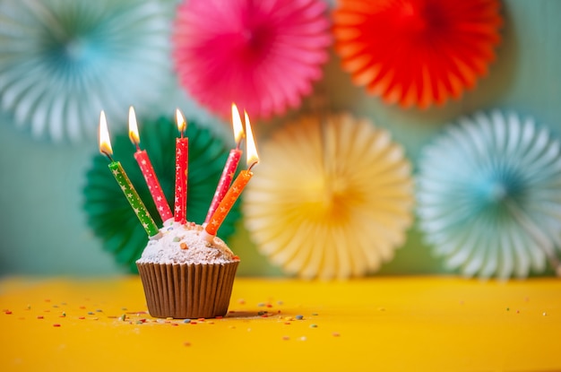 Fête d'anniversaire avec cupcake et bougies colorées.