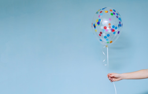 Fête d'anniversaire élégante ou vacances avec des ballons bouchent portrait en studio. Main tenant le ballon multicolore à l'intérieur.