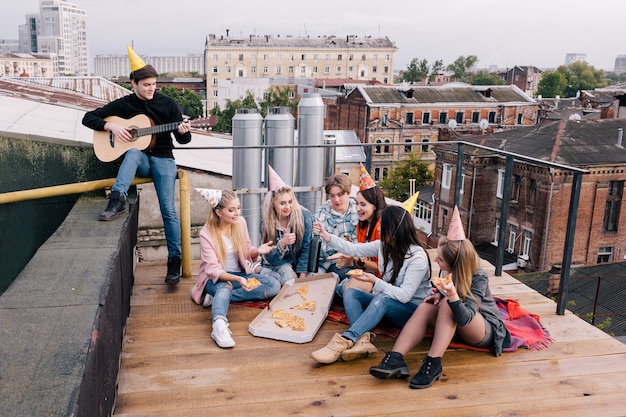 Fête d'anniversaire des étudiants sur le toit. Temps libre. Musique et pizza pour les jeunes