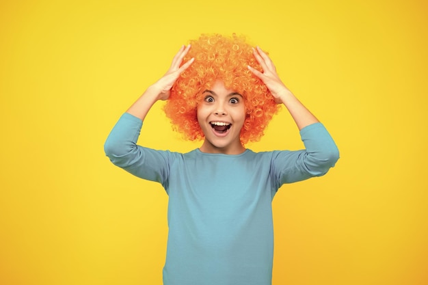 Fête d'anniversaire des filles Enfant drôle en perruque rousse bouclée Il est temps de s'amuser Adolescente aux cheveux orange étant un clown Adolescente excitée heureuse d'émotions étonnées et ravies