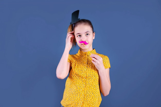 Fête d'anniversaire et jeune fille en chapeaux et accessoires sur mur bleu