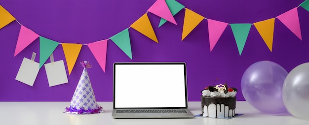 Fête d'anniversaire en ligne avec ordinateur portable à écran blanc, gâteau, chapeau de fête et ballon