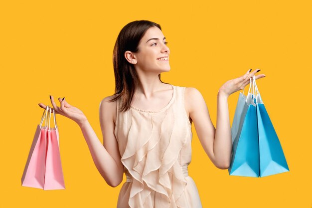 Fête de douche de bébé Concept garçon et fille Heureuse femme tenant des sacs à provisions isolés sur orange Cadeaux pour nouveau-nés Achat en ligne