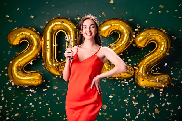 Fête du nouvel an ballons à air confettis femme fond vert avec champagne célébrer