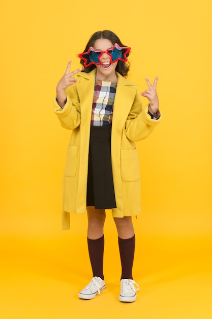 Fête fille Enfant heureux faire des gestes de la main de la victoire Petit enfant célébrer la victoire fond jaune Mignon petit gagnant profiter de la fête de la victoire Concours scolaire Victoire et triomphe