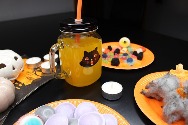 Fête d'Halloween verre avec de la paille d'orange et du soda bonbons effrayants et décoration de collations