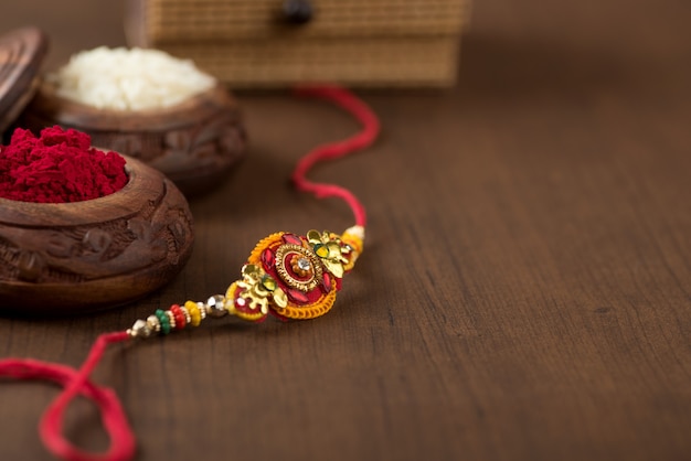 Fête indienne : fond Raksha Bandhan avec un élégant Rakhi, grains de riz et kumkum