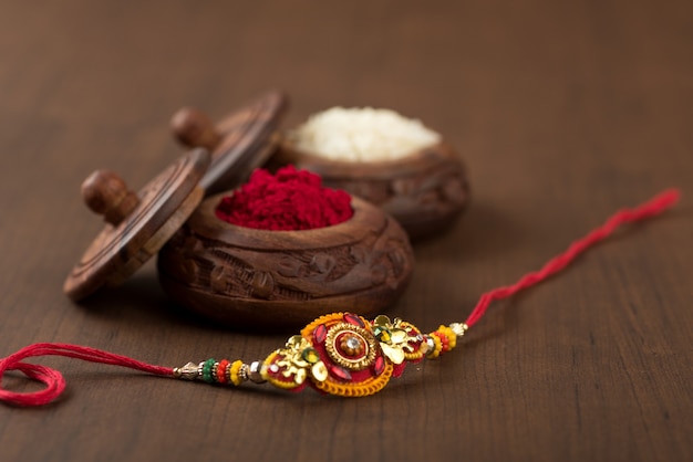 Fête indienne : fond Raksha Bandhan avec un élégant Rakhi, grains de riz et kumkum