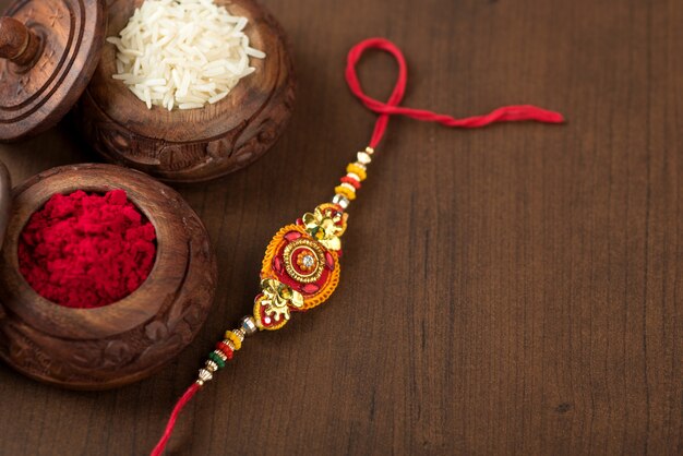 Fête indienne : fond Raksha Bandhan avec un élégant Rakhi, grains de riz et kumkum