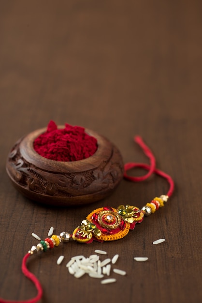 Fête indienne : fond Raksha Bandhan avec un élégant Rakhi, grains de riz et kumkum