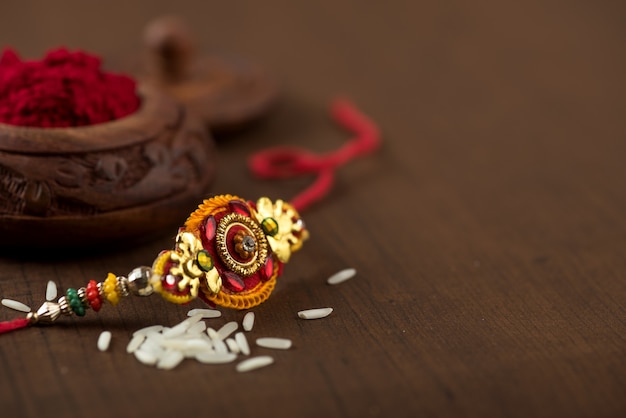 Fête indienne : fond Raksha Bandhan avec un élégant Rakhi, grains de riz et kumkum