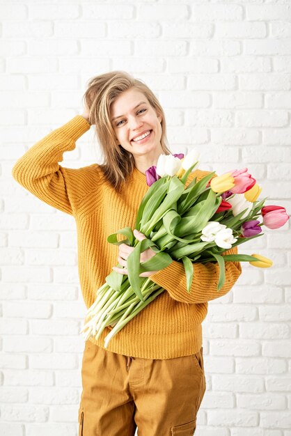 Fête des mères, concept de la journée de la femme. Vacances de printemps. Heureuse jeune femme tenant le bouquet de tulipes