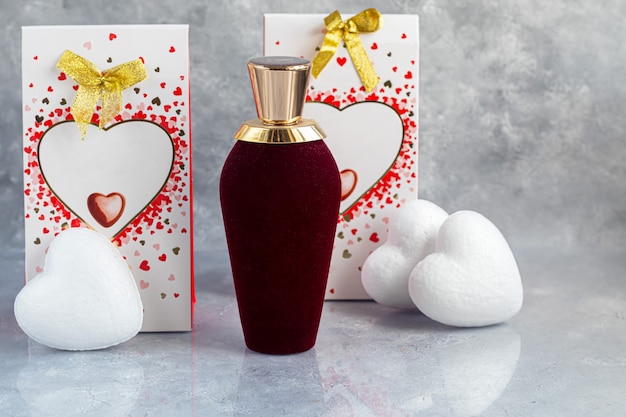 Fête des mères, fête des femmes, Saint-Valentin ou anniversaire. Parfum sur fond gris. Cadeaux, bonbons sous forme de coeurs. Copiez l'espace.