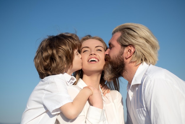 Fête des mères. Parentalité. Famille heureuse. Maternité paternité. Le fils et le papa embrassent la mère. Jeune famille avec enfant. Les enfants adorent.