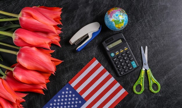 Fête nationale. Bouquet de tulipes, fournitures scolaires et drapeau des États-Unis sur un tableau noir. Retour à l'école