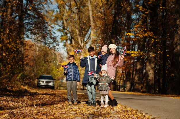 Photo fête nationale du royaume-uni. famille avec des drapeaux britanniques dans le parc d'automne. britishness célébrant le royaume-uni. mère de quatre enfants.