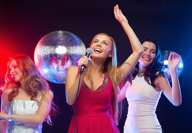 fête, "nouvel an", fête, amis, enterrement de vie de jeune fille, concept d'anniversaire - trois femmes en robes de soirée dansant et chantant karaoké