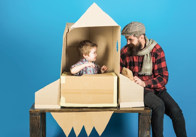 Fête des pères famille heureuse jouant avec fusée en carton et concept de cosmonaute ours en peluche garçon mignon