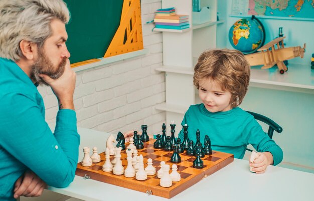 Fête des pères garçon concentré développant une stratégie d'échecs intelligente enfant concentré et pensant tout en