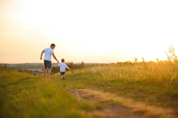 Fête des pères Heureux père de famille et fils en bas âge jouant et riant sur la nature au coucher du soleil