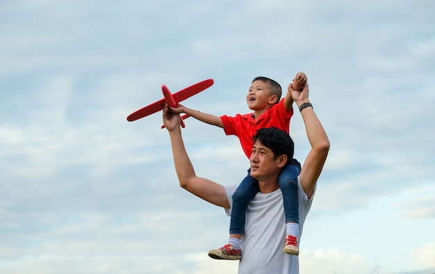 Fête des pères. papa et bébé fils jouant ensemble en plein air avion en papier