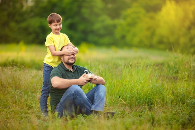 Fête des pères. papa et fils heureux passent du temps ensemble dans la nature, l'enfant donne un cadeau à son père