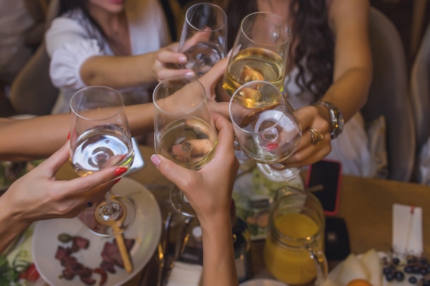 Fête. Personnes tenant des verres de vin blanc portant un toast.