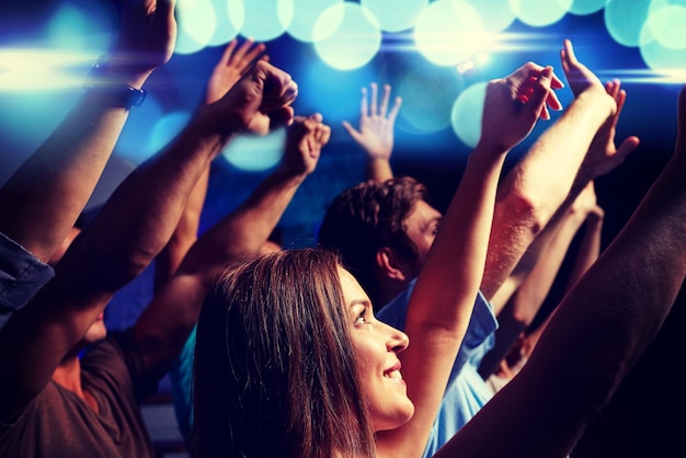 Photo fête, vacances, célébration, vie nocturne et concept de personnes - amis souriants agitant la main au concert en club
