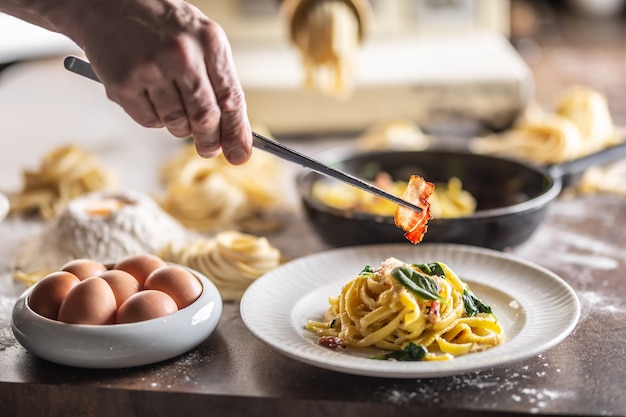 Fettuccine au basilic frais garnie d'un morceau de bacon cuit dessus avec une pince à épiler.