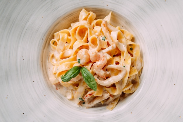 Fettuccine de pâtes italiennes dans une sauce crémeuse aux crevettes sur une assiette